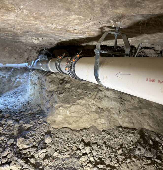 Underground sewer line repair showing exposed PVC piping at a Ruben's Plumbing Services job site.